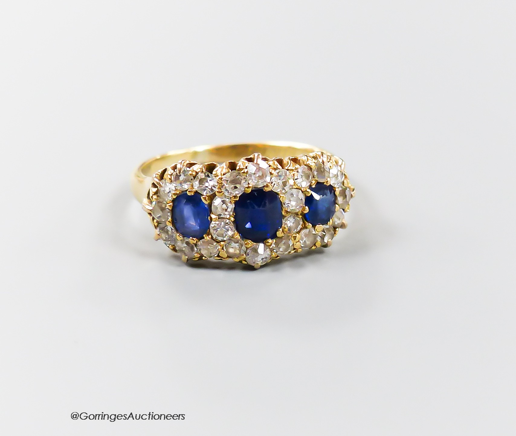 A late Victorian yellow metal, sapphire and diamond set triple cluster ring, with shank inscription, size M, gross weight 3.7 grams.